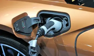 Connettore di ricarica inserito in un'auto, illustra il plug in hybrid significato: un veicolo che unisce motore elettrico e a combustione.