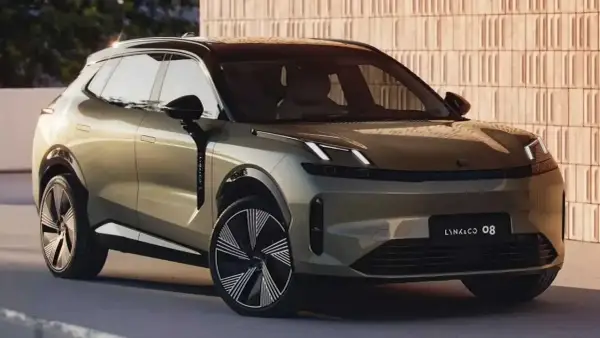 SUV Lynk & Co 08 color oro, con cerchi dal design audace, parcheggiato davanti a un muro di mattoni.